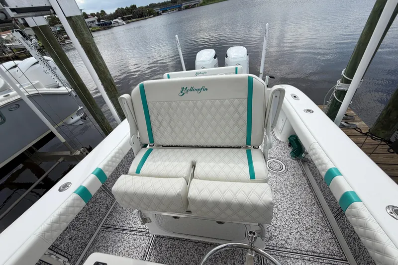 Slide: The Image of 2002 Yellowfin 31 Center Console boat with white and teal seating, docked by the water. - 46