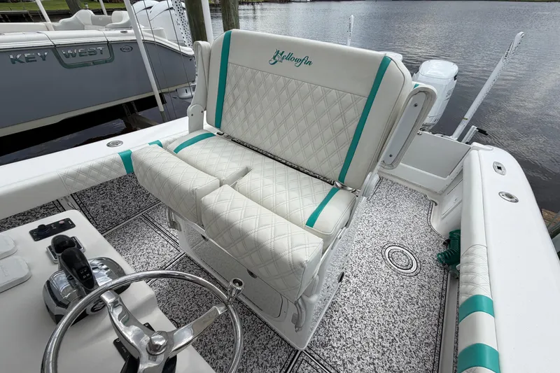 Slide: The Image of 2002 Yellowfin 31 Center Console boat interior with white and teal seating, docked by water. - 45