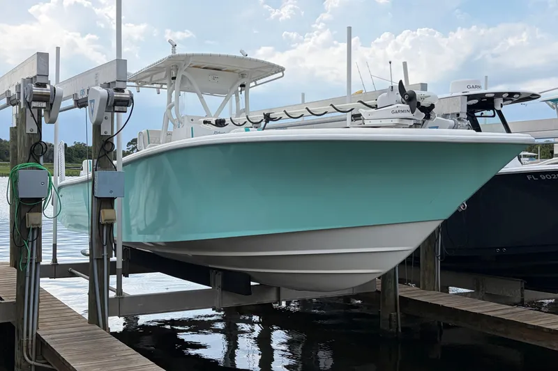 Slide: The Image of 2002 Yellowfin 31 Center Console boat on lift, turquoise hull, docked by water. - 0