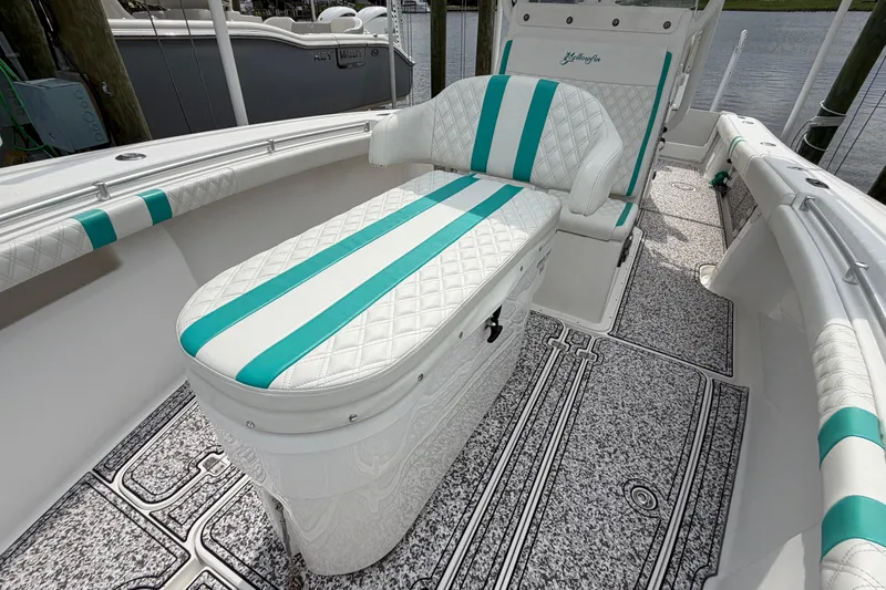 Slide: The Image of 2002 Yellowfin 31 Center Console boat with teal and white seating, docked by the water. - 39
