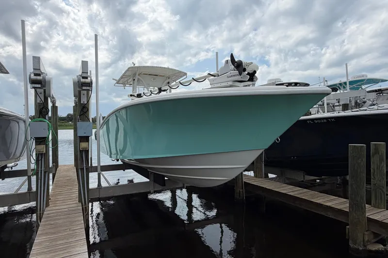 Slide: The Image of 2002 Yellowfin 31 Center Console boat on lift, docked under cloudy sky. - 4