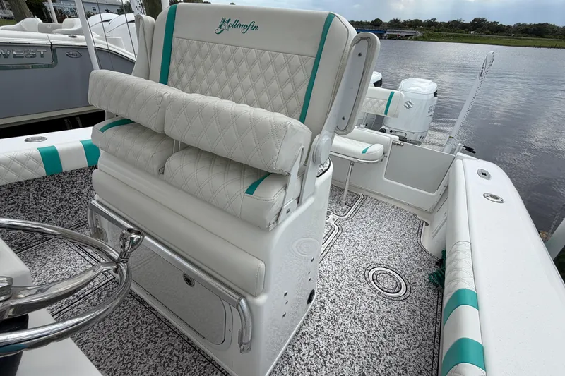 Slide: The Image of 2002 Yellowfin 31 Center Console boat with white and teal seating, docked by the water. - 24