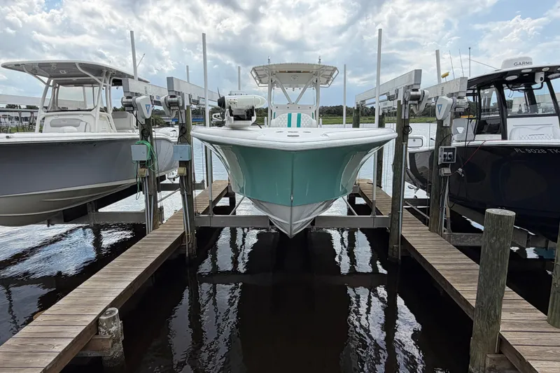 The Image of 2002 Yellowfin 31 Center Console boat docked between two others on a sunny day. - 3