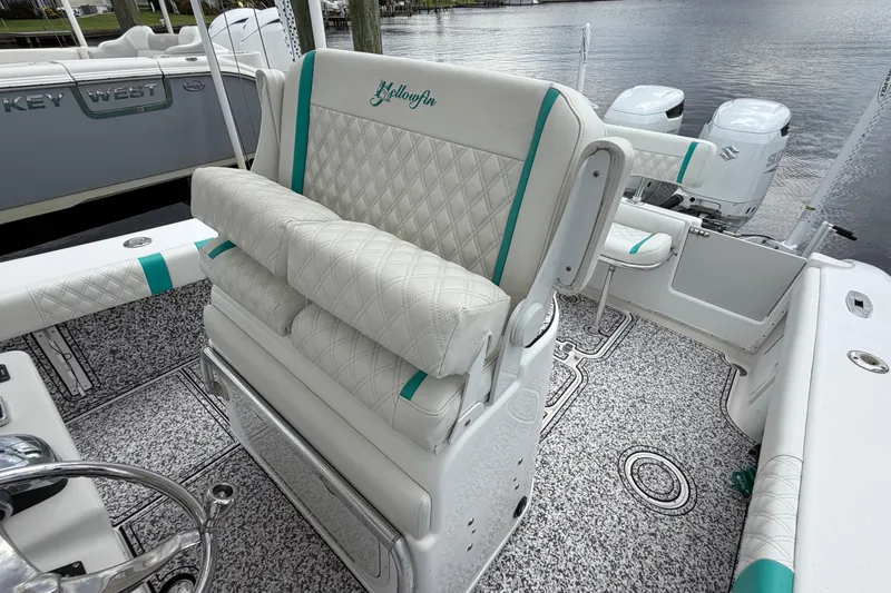 Slide: The Image of 2002 Yellowfin 31 Center Console boat with white and teal seating, docked by the water. - 23