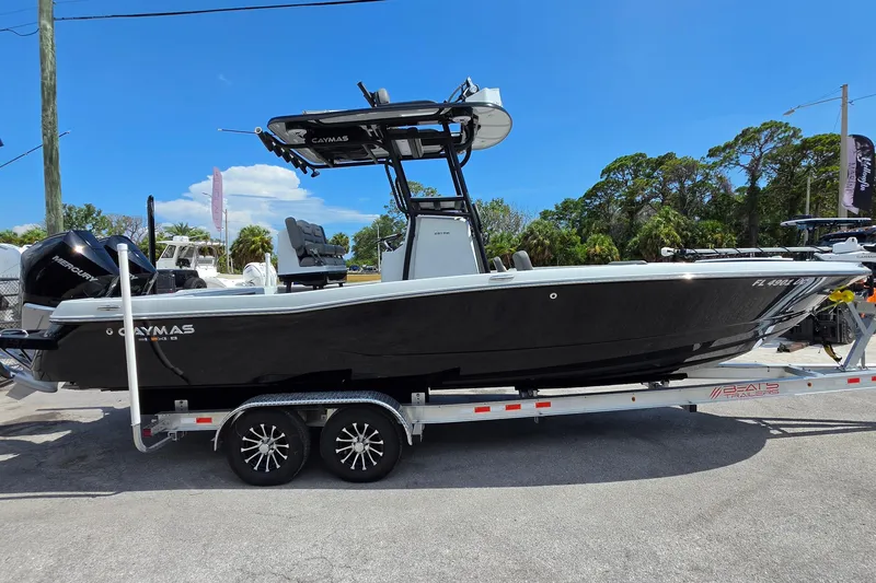 Slide: The Image of 2025 Caymas 281 HB boat on trailer, sleek black design, parked outdoors under blue sky. - 6