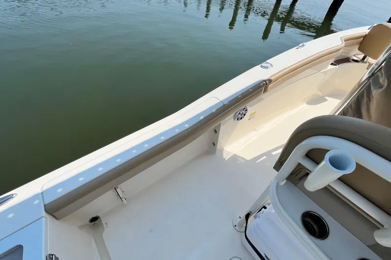 Slide: The Image of 2021 Scout 215 XSF boat interior with seating and cup holder, docked on calm water. - 14