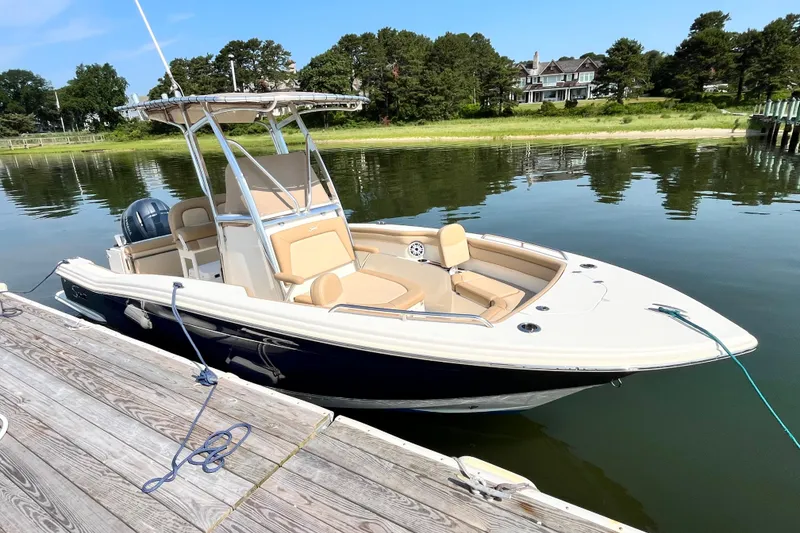 Slide: The Image of 2021 Scout 215 XSF boat docked on calm water, surrounded by greenery. - 6