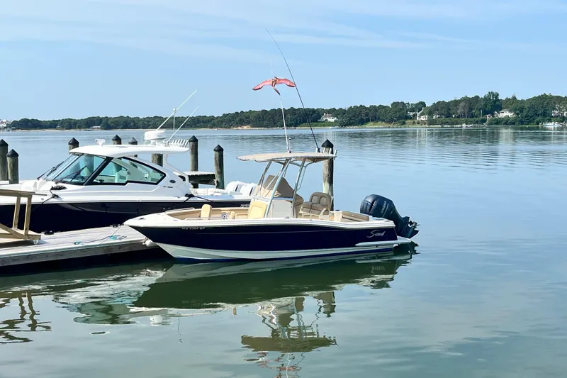Slide: The Image of 2021 Scout 215 XSF boat docked on calm water, clear sky background. - 1