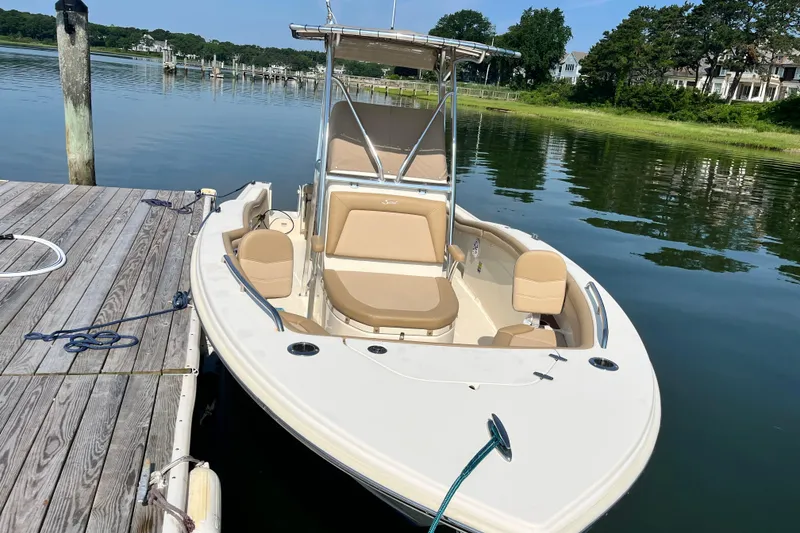 Slide: The Image of 2021 Scout 215 XSF boat docked on calm water, featuring beige seating and sleek design. - 5
