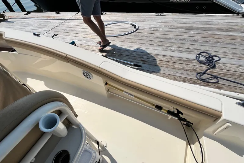 Slide: The Image of 2021 Scout 215 XSF boat docked, featuring interior seating and fishing rod holder. - 15