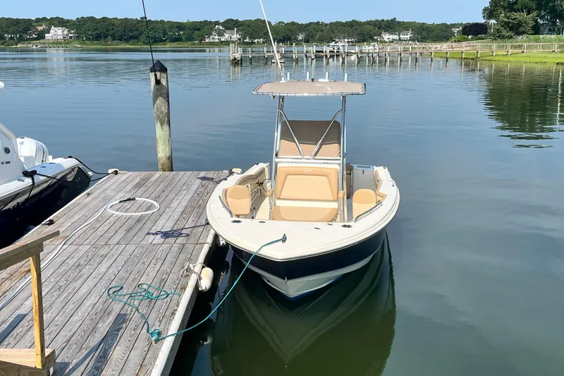 Slide: The Image of 2021 Scout 215 XSF boat docked on calm water with scenic background. - 4