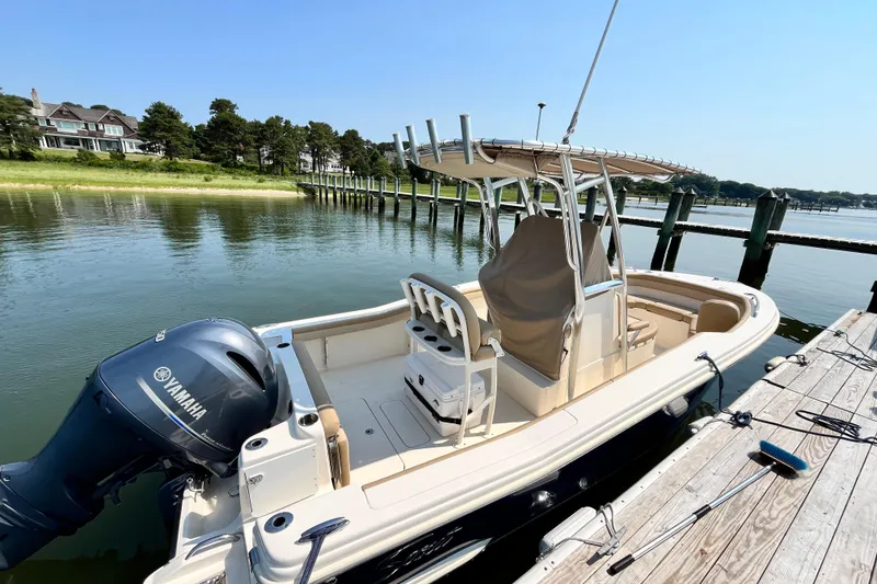 Slide: The Image of 2021 Scout 215 XSF boat docked by a serene waterfront with Yamaha engine. - 8