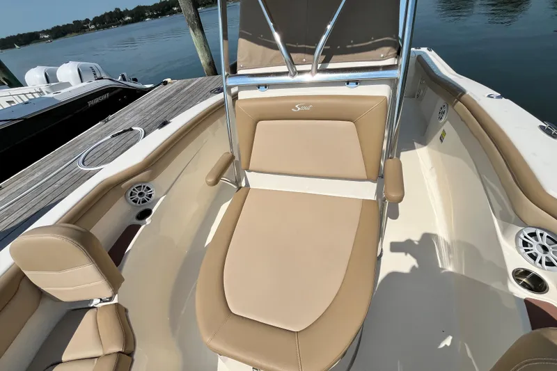 Slide: The Image of 2021 Scout 215 XSF boat interior with tan seating and sleek design at a dock. - 25