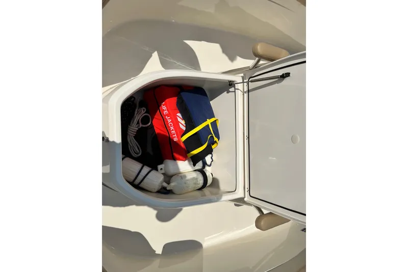 Slide: The Image of Storage compartment on 2021 Scout 215 XSF boat with life jackets and accessories. - 30