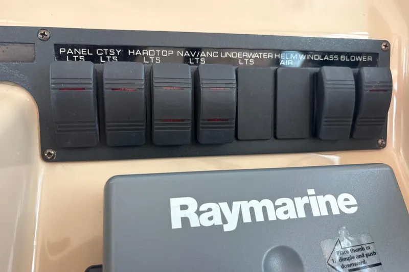 Slide: The Image of Control panel of a 2012 Tiara Yachts 3900 Sovran with labeled switches and Raymarine device. - 28