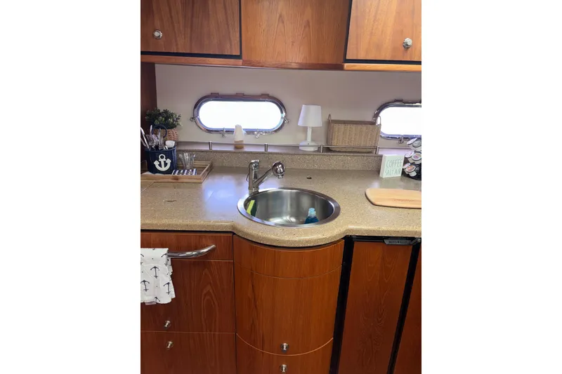 Slide: The Image of 2012 Tiara Yachts 3900 Sovran kitchen with wooden cabinets, sink, and nautical decor. - 46