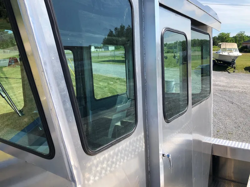 Slide: The Image of A modern workboat with large windows and sturdy metal frame, parked on a gravel lot. - 9