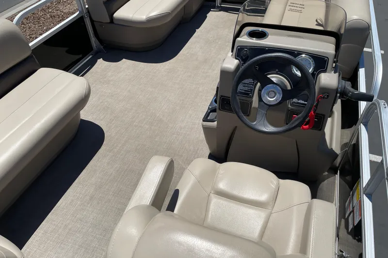 Slide: The Image of 2025 Sun Tracker Party Barge 16 DLX interior with beige seating and steering console. - 13