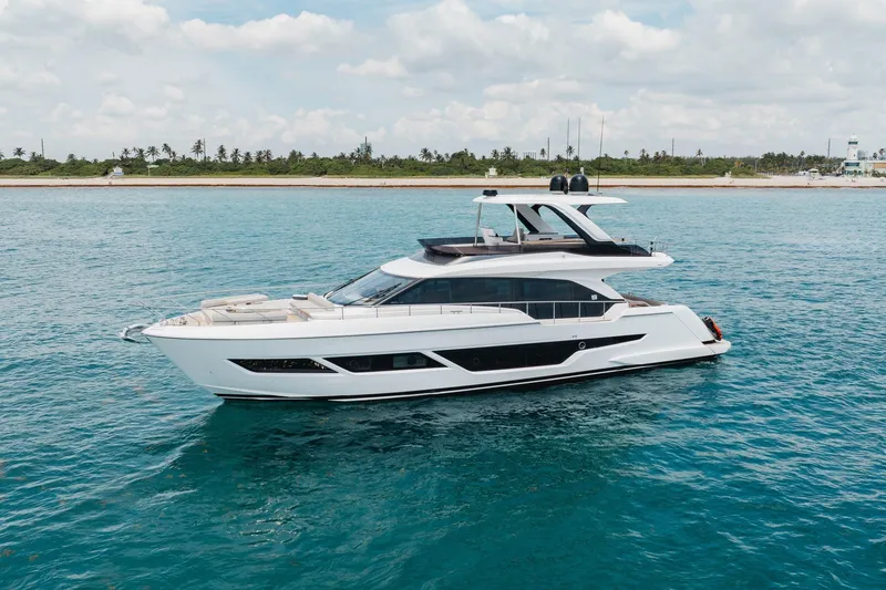 The Image of 2025 Ferretti Yachts 670 cruising on clear blue waters near a tropical shoreline. - 1
