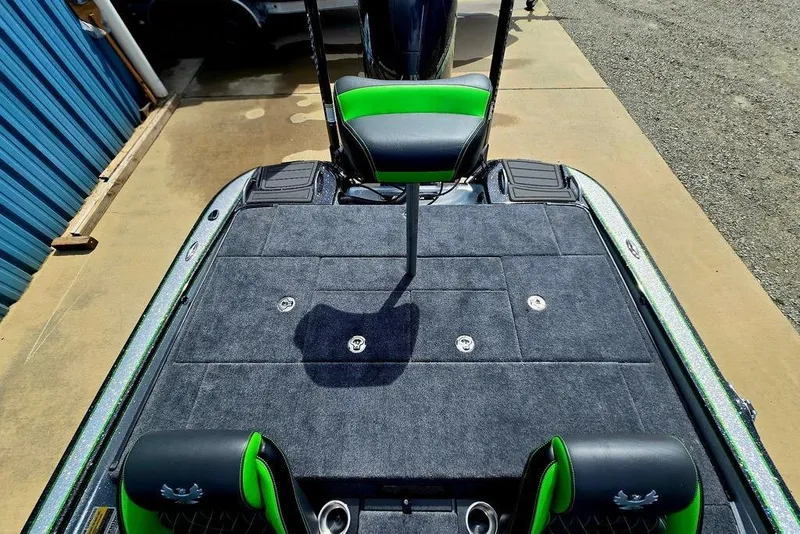 Slide: The Image of 2027 Phoenix 721 ZXL boat deck with green accents and seating, parked on concrete. - 69