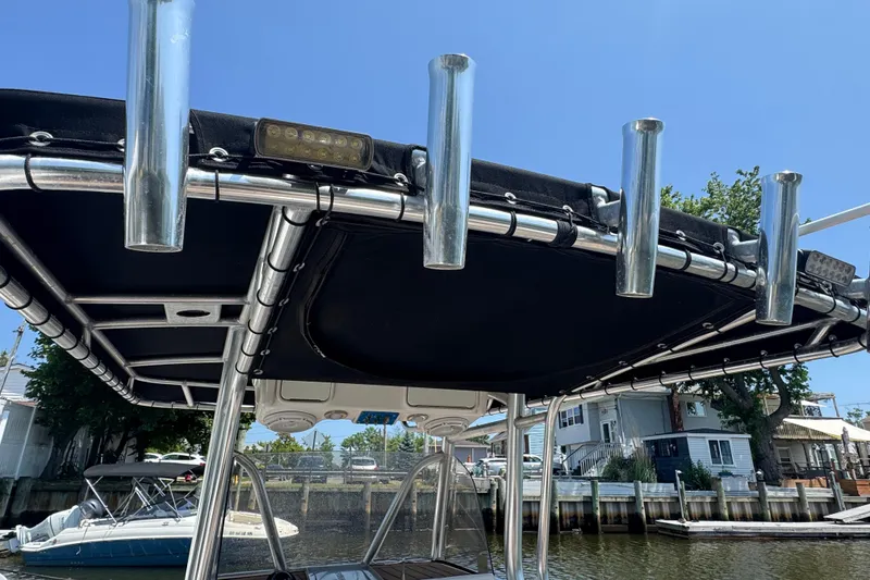 Slide: The Image of 2014 Century 2301 Center Console boat with rod holders and canopy, docked by waterfront homes. - 8