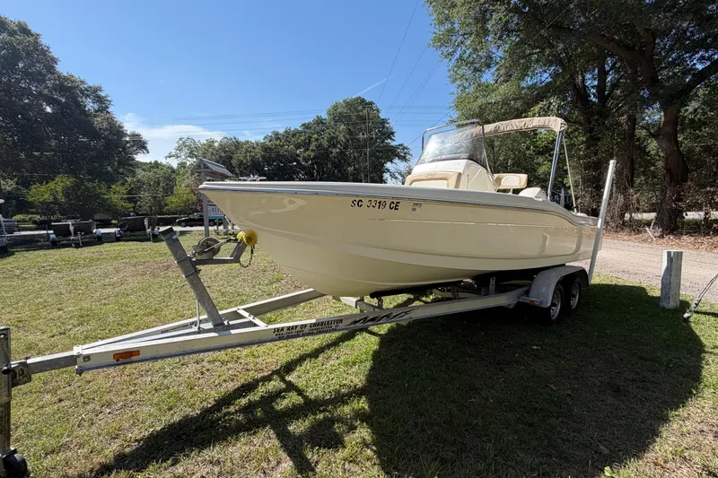 Slide: The Image of 2012 Scout 210 XSF boat on trailer, parked on grass, surrounded by trees. - 6
