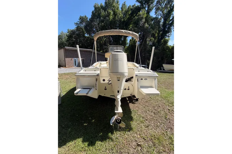 Slide: The Image of 2012 Scout 210 XSF boat with outboard motor, parked on grass, surrounded by trees. - 8