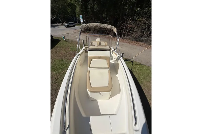 Slide: The Image of 2012 Scout 210 XSF boat with beige seating, parked on grass near a road. - 9
