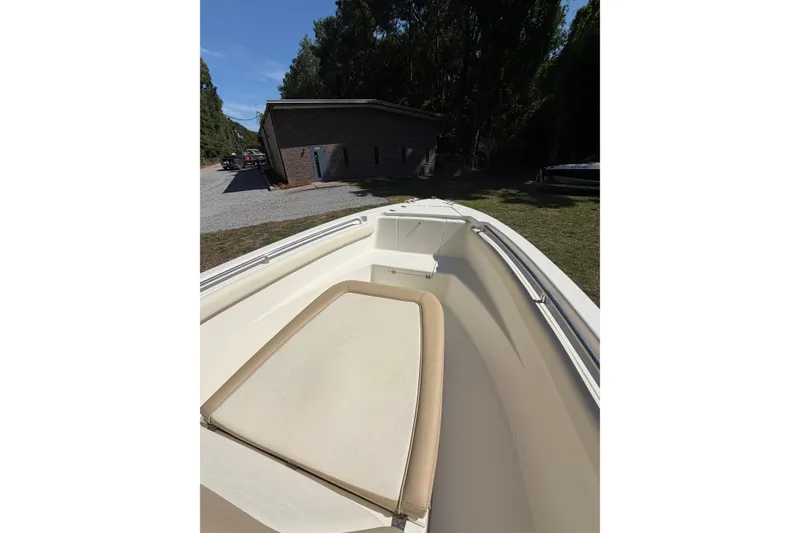 Slide: The Image of 2012 Scout 210 XSF boat interior with cushioned seating, parked near a building. - 11
