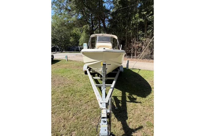 Slide: The Image of 2012 Scout 210 XSF boat on trailer, parked on grassy area with trees in background. - 7