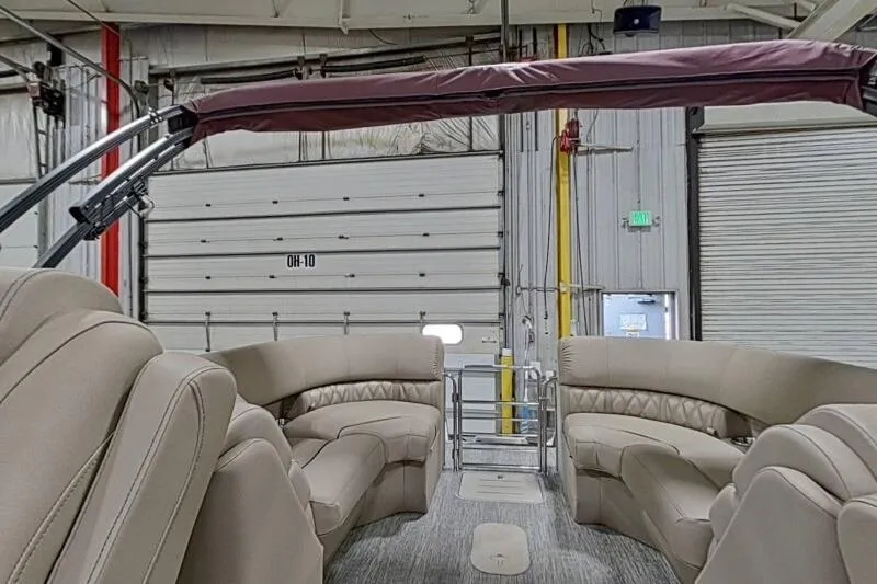 Slide: The Image of 2026 Bennington 24 LXS Quadbench interior with plush seating in a spacious boat showroom. - 4