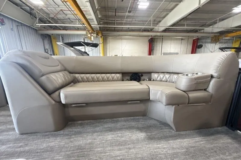 Slide: The Image of 2026 Bennington 24 LXS Quadbench interior with luxurious beige seating in a spacious showroom. - 6