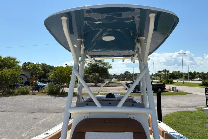 Slide: The Image of 2027 Pioneer 202 Islander boat with T-top, parked outdoors under a clear blue sky. - 27