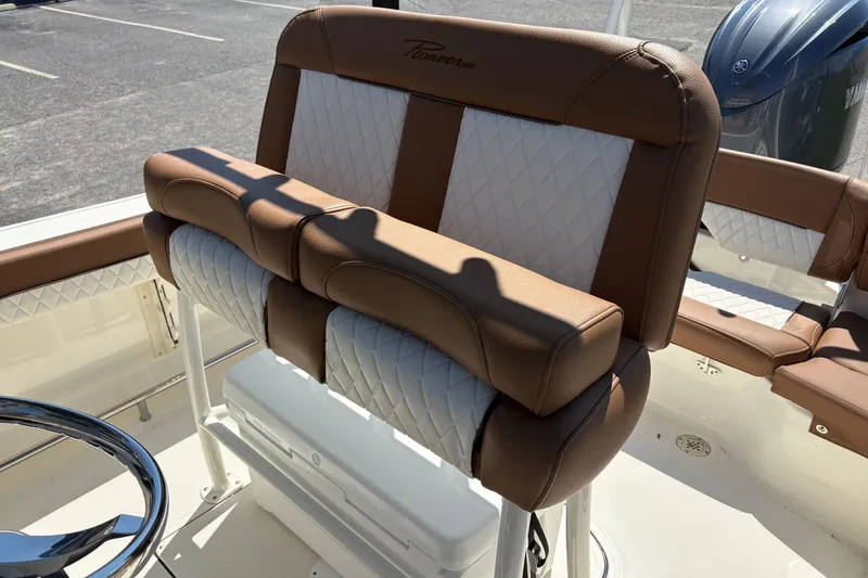 Slide: The Image of 2027 Pioneer 202 Islander boat seat with brown and white upholstery, parked outdoors. - 12