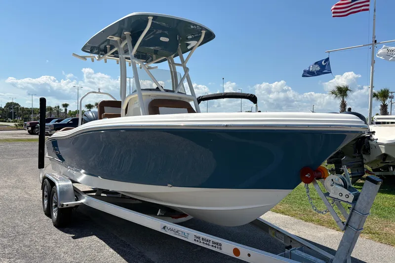 Slide: The Image of 2027 Pioneer 202 Islander boat on trailer, displayed outdoors with flags in background. - 5
