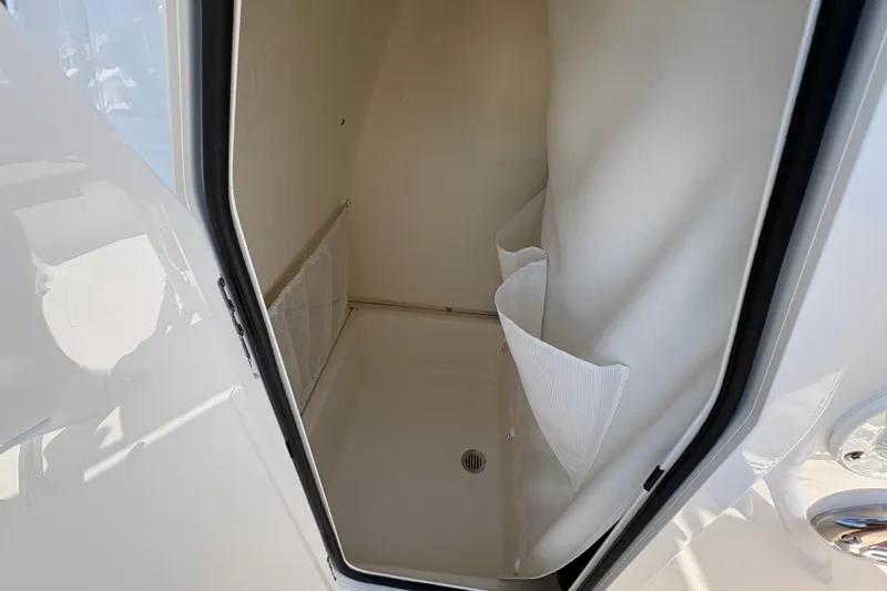 Slide: The Image of Interior storage compartment of 2027 Pioneer 202 Islander boat, featuring white lining and drainage. - 24