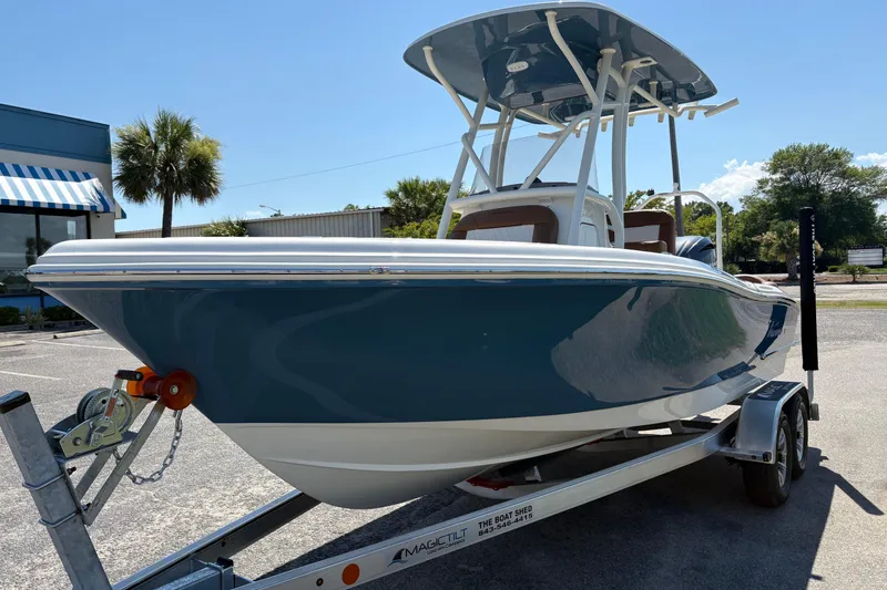 Slide: The Image of 2027 Pioneer 202 Islander boat on trailer, parked outdoors under clear blue sky. - 7