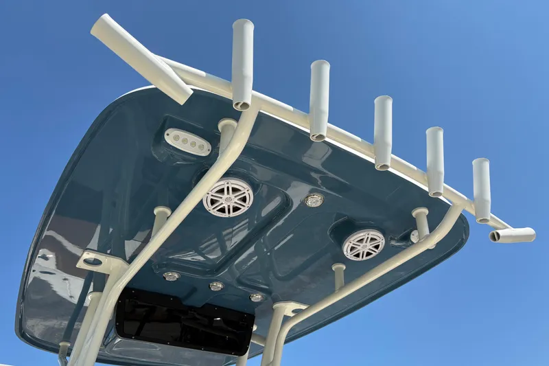 Slide: The Image of 2027 Pioneer 202 Islander boat top with rod holders and speakers against blue sky. - 14