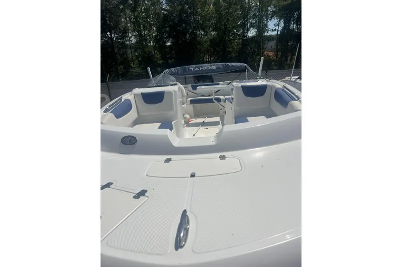 Slide: The Image of 2017 Tahoe 2150 boat interior with white and blue seating, surrounded by trees. - 4