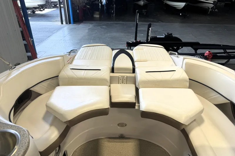 Slide: The Image of 2008 Four Winns H240 boat interior with white cushioned seating in a garage setting. - 11