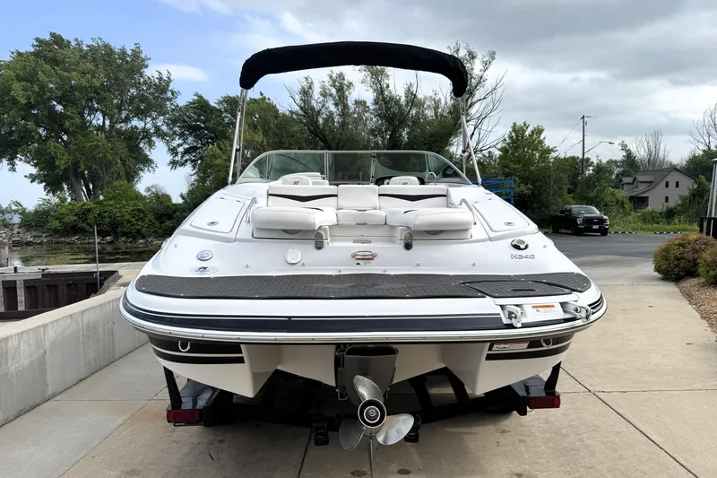 Slide: The Image of 2008 Four Winns H240 boat with white seating, docked on a concrete ramp, surrounded by trees. - 4