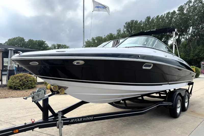 Slide: The Image of 2008 Four Winns H240 boat on trailer, sleek black design, parked outdoors. - 2