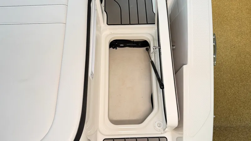 Slide: The Image of An open storage compartment on a 2026 Sea Ray SPX 210 boat with cushioned seating. - 13