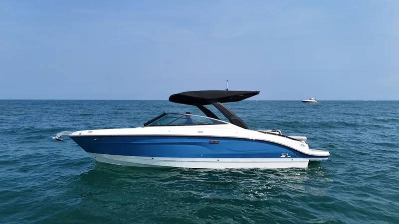 The Image of A 2027 Sea Ray SLX 280 on calm water with a blue hull and black canopy. - 0