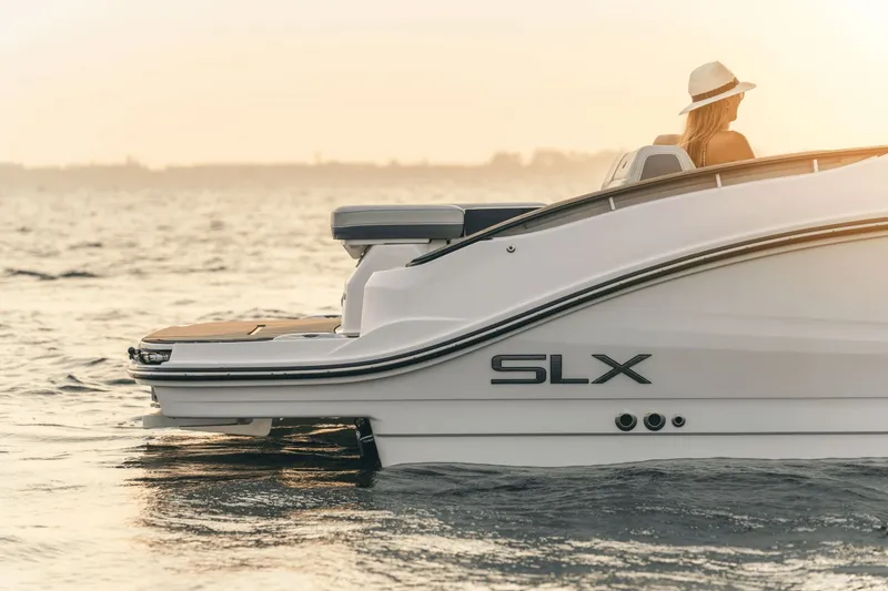 Slide: The Image of A woman sits on a Sea Ray SLX 280 boat at sunset on the water. - 26