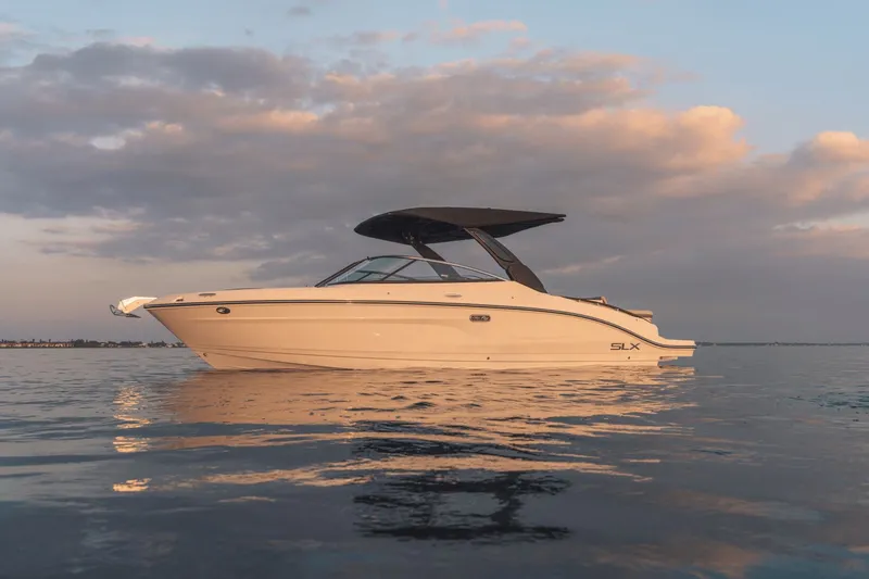 Slide: The Image of A sleek 2027 Sea Ray SLX 280 boat glides over calm water at sunset. - 29