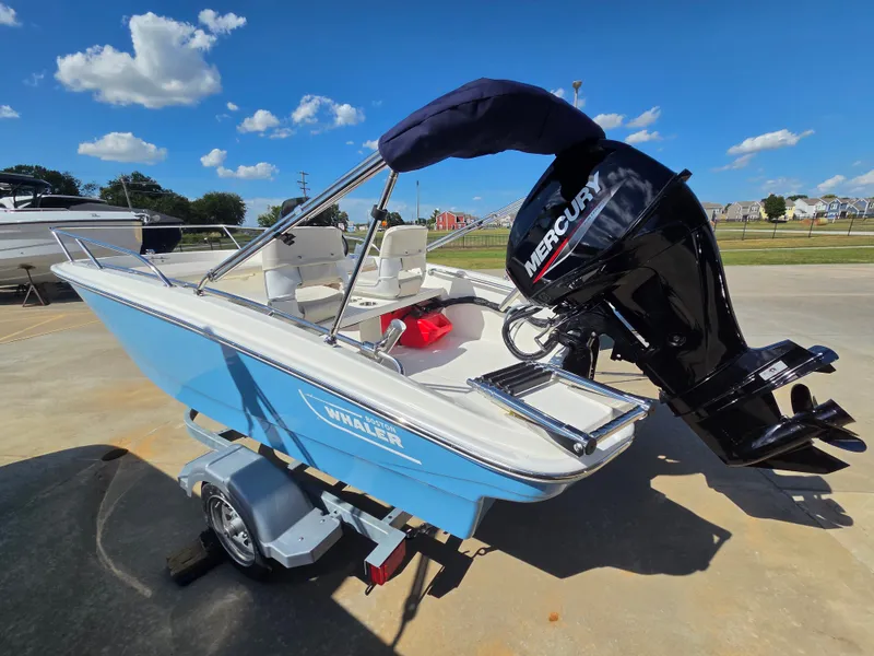 Slide: The Image of A 2027 Boston Whaler 130 Super Sport with a blue hull and Mercury outboard motor on a trailer. - 7