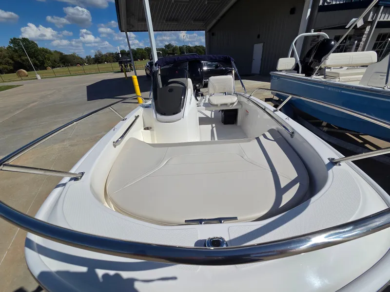 Slide: The Image of The image shows a 2027 Boston Whaler 130 Super Sport boat. It features an open deck with seating and is parked in a modern harbor area. - 5