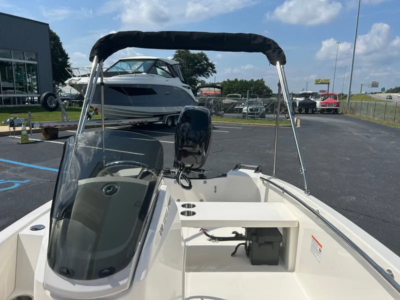 Slide: The Image of A 2027 Boston Whaler 130 Super Sport on a parking lot. It features a black Bimini top. - 12