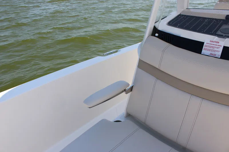 Slide: The Image of A section of a Boston Whaler 250 Dauntless boat with beige seating and armrest by the water. - 17